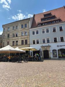 ein großes Gebäude mit Tischen und Sonnenschirmen davor in der Unterkunft TraumFerienwohnung "Am Markt" in Pirna - Sächsische Schweiz in Pirna