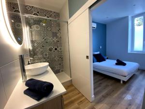 a bathroom with a sink and a bed in a room at LA PERLE BLEUE, Centre ville Valence,Proche gare in Valence