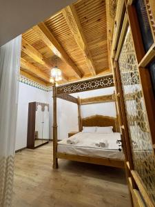 a bed in a room with a wooden ceiling at Hotel Khalid in Bukhara