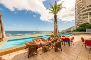 a patio with a pool and chairs and a palm tree at Oceana Suites Eurovista in Viña del Mar