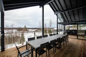 a long table and chairs on a deck with a view at BestVillas Himos Finland in Jämsä
