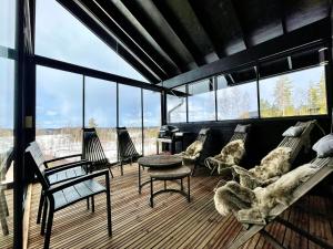 a living room with chairs and a table and windows at BestVillas Himos Finland in Jämsä