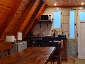 cocina con mesa de madera y microondas en La Amarilla Casa de Huéspedes Ruta 40 Montañas en Epuyén