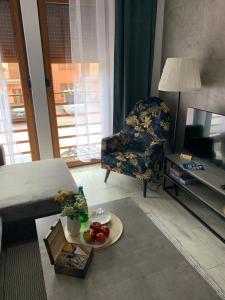 una sala de estar con una cama y una silla con un plato de fruta en Przy Złotych Piaskach en Sława