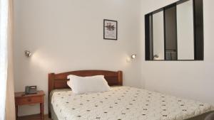 1 dormitorio con cama y espejo en la pared en RADAMA Hotel, en Antananarivo