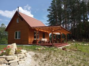 eine Blockhütte mit einer Veranda und einem Dach in der Unterkunft Domek w lesie in Biłgoraj