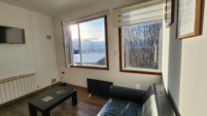 a living room with a couch and a table and two windows at Departamento Los Fueguinos - Ushuaia in Ushuaia