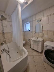 een badkamer met een bad, een wastafel en een wasmachine bij Wileńska Pokoje in Słupsk