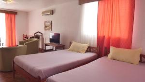 Zimmer mit 2 Betten, einem Stuhl und einem TV in der Unterkunft Radama Hotel in Antananarivo