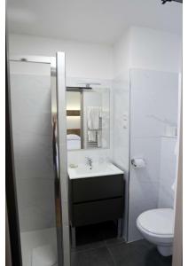 a white bathroom with a sink and a toilet at Hôtel Belleville in Lamalou-les-Bains
