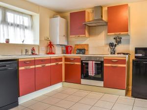 una cocina con armarios rojos y un aparato negro en Roseus - Uk44706 en Combe Martin