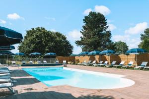 a swimming pool with lounge chairs and umbrellas at Les Jardins de Deauville in Saint-Martin-aux-Chartrains