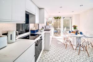 a kitchen with white cabinets and a table with chairs at Marina Bridge House Central Cowes in Cowes