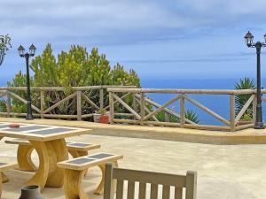 a picnic table and benches with a view of the ocean at TENERIFE ECOLIFE HOUSES by APARTAMENTOS ESTRELLA DEL NORTE in Garachico
