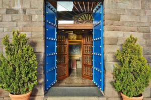 Palacio del Inka, a Luxury Collection Hotel, Cusco في كوسكو: مدخل لمبنى بأبواب زرقاء وأشجار الفخار