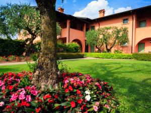 ein Baum und Blumen vor einem Gebäude in der Unterkunft BellaSirmione Holiday Apartments in Sirmione