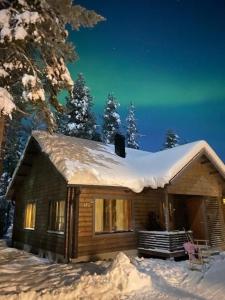 una cabaña de madera con nieve en el techo. en Kantokelo en Ylläsjärvi