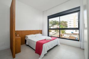 a bedroom with a bed and a large window at Studio para casais bem localizado ARE504 in Florianópolis