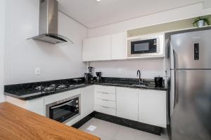 a kitchen with white cabinets and a stainless steel refrigerator at Studio para casais bem localizado ARE504 in Florianópolis