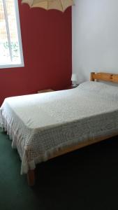 - une chambre avec un lit blanc et un mur rouge dans l'établissement Maria Delicia, à Godoy Cruz