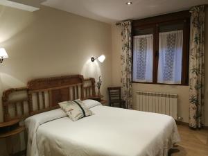 a bedroom with a white bed and a window at Hotel rural La Campanona in Villager de Laciana