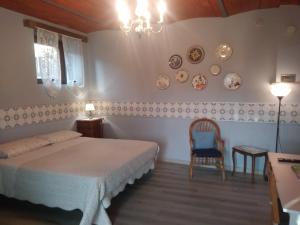 1 dormitorio con cama, silla y platos en la pared en Segarati Relax La Maiolica, en Bardi