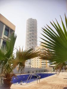 a tall building in the background with palm trees in the foreground at Cozy Apartment in Jumeirah Village Circle, Dubai. in Dubai