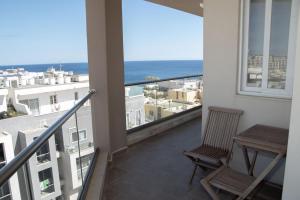 balcón con mesa y vistas al océano en Graziosa Penthouse en Il-Ħamrija