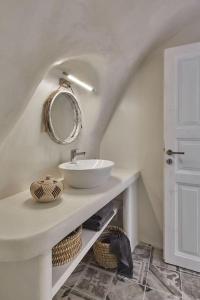 a white bathroom with a sink and a mirror at Villa Agalitsa Cave Houses with Garden Courtyard in Megalochori