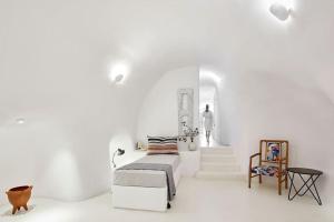 a white room with a bed and a staircase at Villa Agalitsa Cave Houses with Garden Courtyard in Megalochori