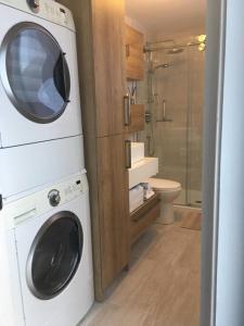 a bathroom with a washing machine and a toilet at Floral'Anse in LʼAnse-Saint-Jean