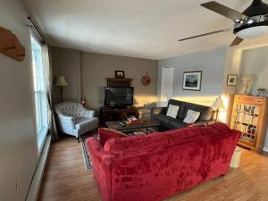 a living room with a red couch and a tv at Floral'Anse in LʼAnse-Saint-Jean