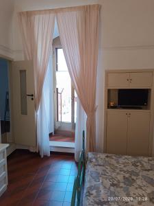 Schlafzimmer mit einem Bett und einem Fenster mit Vorhängen in der Unterkunft Locazione turistica La vecchia arcata in Noci