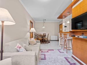 uma sala de estar com um sofá e uma cozinha em Araucárias 302 em Gramado