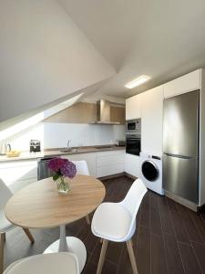 a kitchen with a wooden table and white chairs and a kitchen with a refrigerator at Apto Solpor, terraza y parking in Cambados