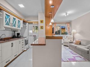 cocina y sala de estar con armarios blancos y sofá en Araucárias 302, en Gramado