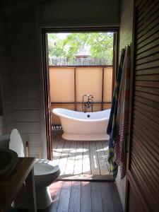 baño con bañera, aseo y ventana en Rotten Hill Retreat Cottages, en English Harbour Town