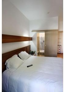 ein Schlafzimmer mit einem weißen Bett mit Fernbedienung in der Unterkunft Hôtel Belleville in Lamalou-les-Bains