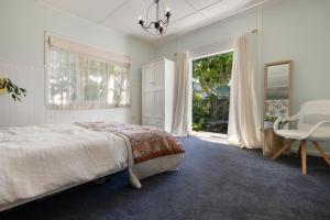 a bedroom with a bed and a table and a chair at The Country Beach Oasis in Papamoa