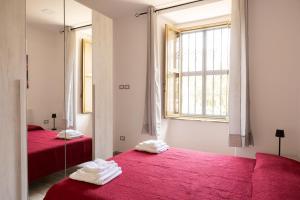 a room with two beds with red sheets and a window at Domus Re Ferdinando - AIRPORT in Naples
