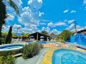 un complejo con 2 piscinas con sillas y sombrillas en Hotel Campestre La Primavera del Quindío, en Montenegro