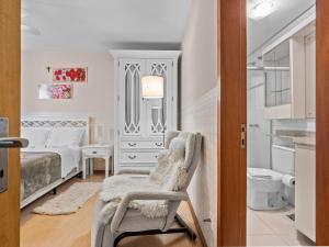 1 dormitorio blanco con 1 cama y 1 silla en Araucárias 302, en Gramado