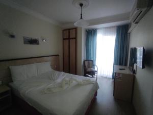 a bedroom with a white bed and a window at AYHAN OTEL in Çeşme