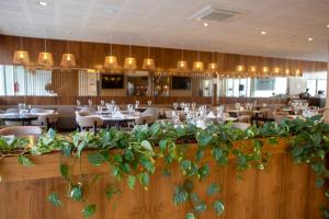 un restaurante con mesas, sillas y plantas en Hotel Cálido Termal en Termas de Río Hondo