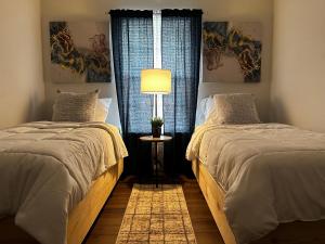a bedroom with two beds and a lamp and a window at Modernized Stay in Eagle Pass