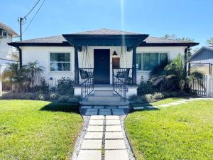 a white house with a front door and a grass yard at Luxury - Pet Friendly, Farmhouse Bungalow DT Tampa in Tampa