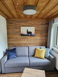 a couch in a living room with a wooden wall at Bergkristall B&B in Berwang