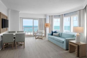 a living room with a blue couch and a table with chairs at Bethany Beach Ocean Suites Residence Inn by Marriott in Bethany Beach