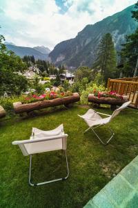 two chairs and a table on a field with flowers at Suites Courmayeur - Mont Blanc in Courmayeur