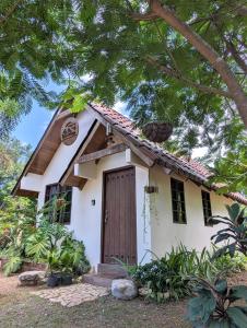 a small white house with a brown door at Didi Lodge - Cabaña cálida y acogedora! in Cañas